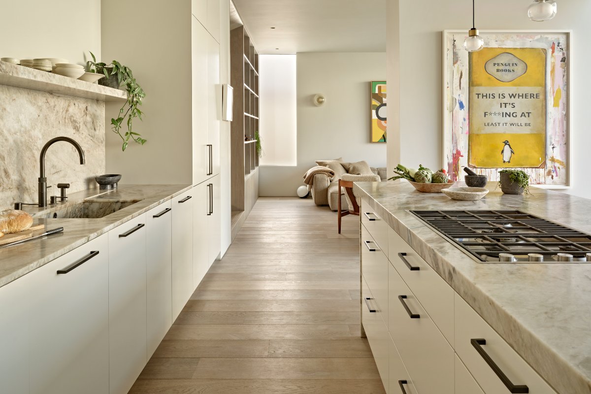 View of the cooking zone with a gas hob and a sink area, looking into a sitting room.