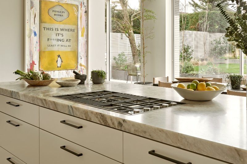 A closeup at the kitchen island with storage drawers and a gas hob, looking into the garden.