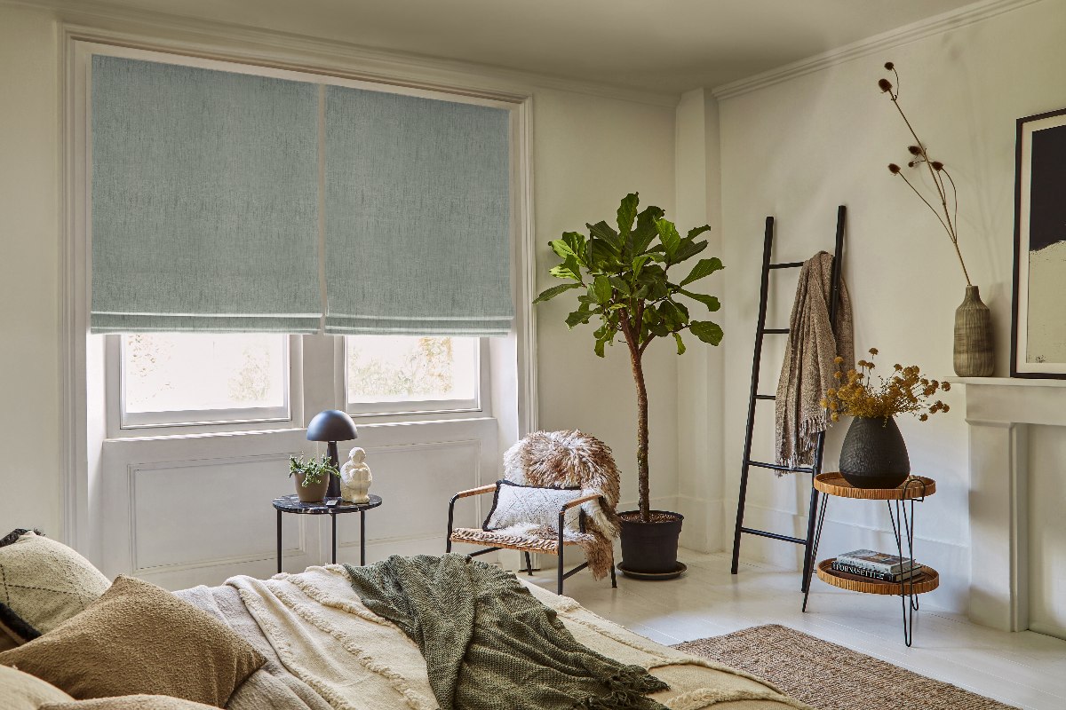 A Scandi bedroom with textured furnishings and blue roller blinds.