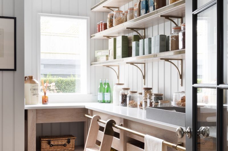 Walk-in pantry with classic panelling, a ladder for reaching top shelves, and decanted jars on display.