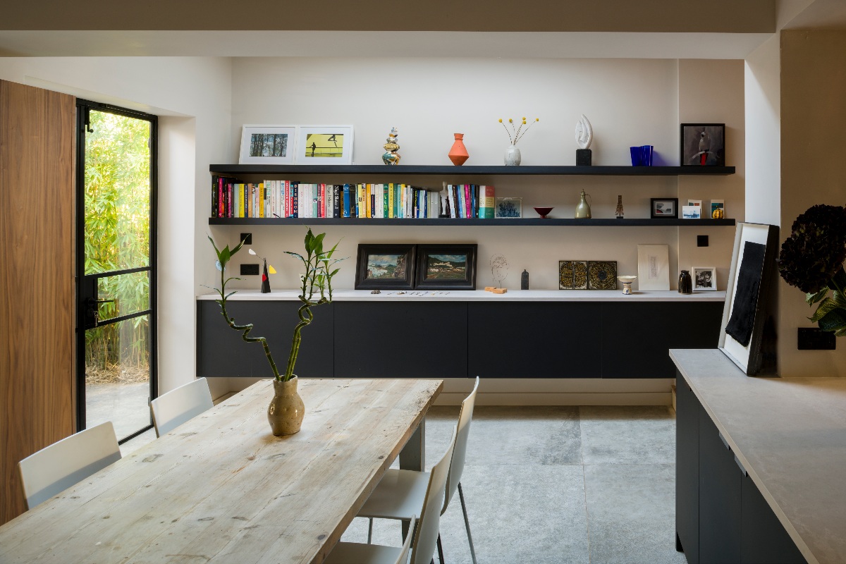 Dining space in a mid-century modern kitchen with dark units and natural materials.