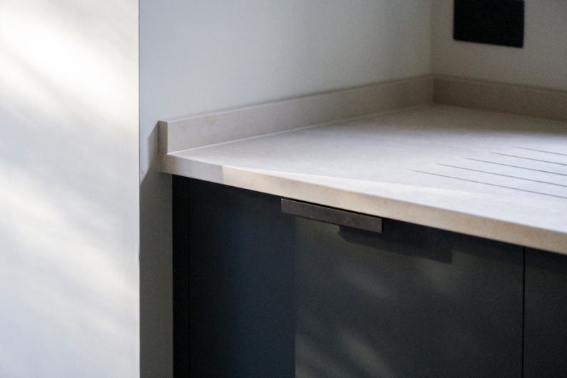 Closeup at the base cupboard painted in black with concrete-effect worktop.