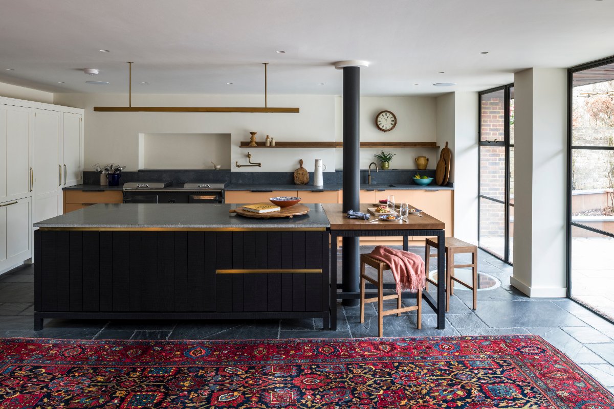 Black and oak cabinetry with metallic trims, soapstone worktops, sleek lighting, and steel-framed glazing.