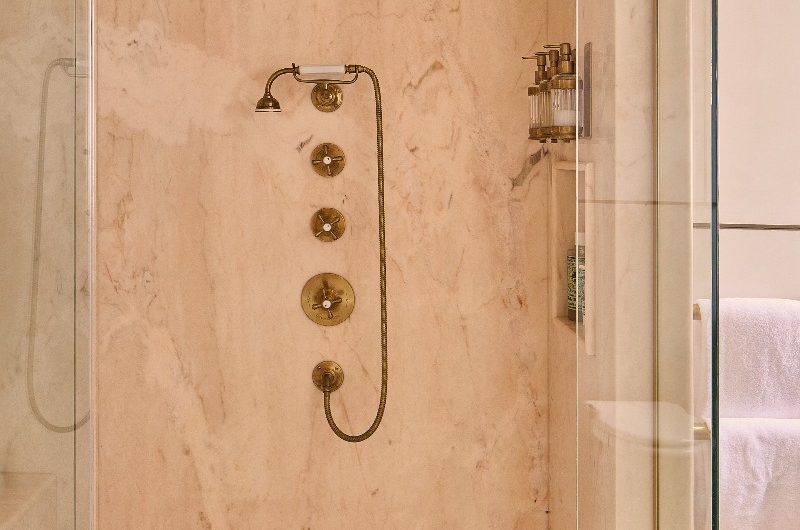 Shower room with classic brassware, a storage niche for toiletries, a marble seat and wall-mounted brushed brass bottle dispensers.