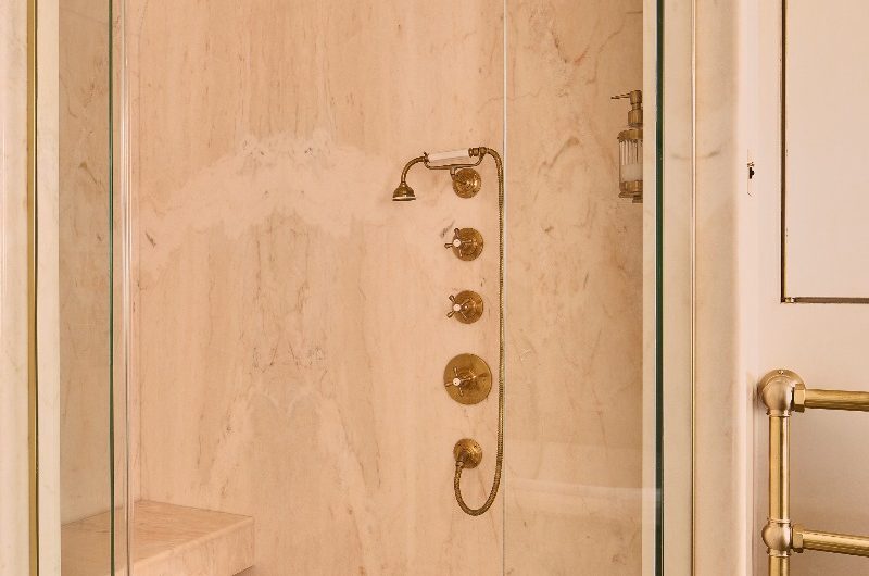 Shower room with curved ceiling, classic brassware, wall-mounted dispensers, a shower seat, and gold framed enclosure in Kate Moss' bathroom.