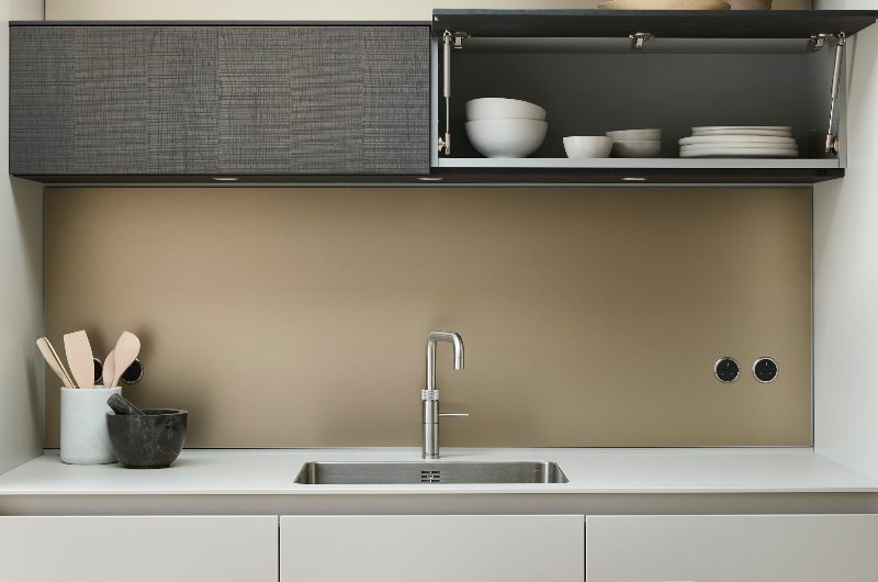 A modern scheme with handleless furniture, a wet zone with an inset sink and chrome tap and wall-mounted storage.