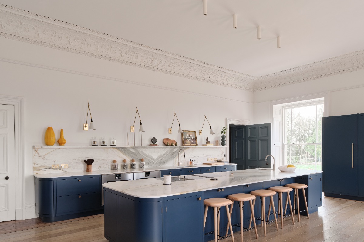 A blue scheme with modern cabinetry, veiny surfaces, wall lights, and tall ceiling.