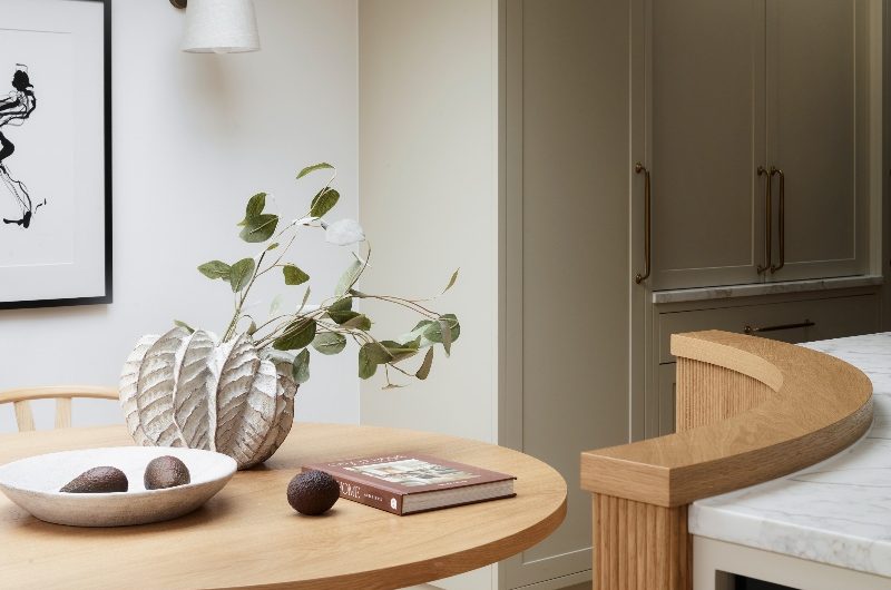 Closeup at the island seating with a bespoke bench with a fluted dining table and wood chairs.