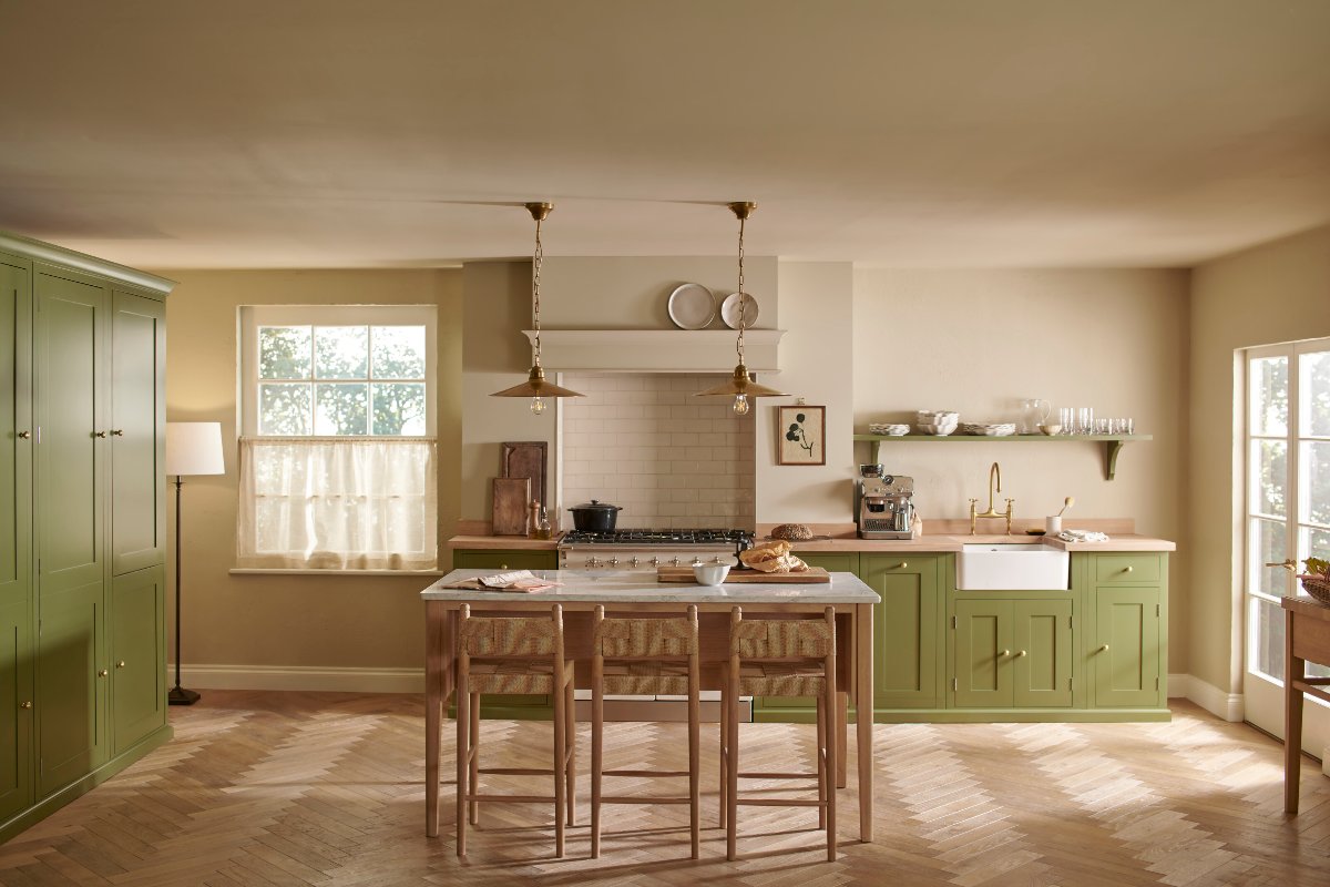 A calm, scandi scheme with green cabinetry, wood worktops and flooring, a freestanding island with seating.