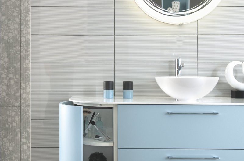 Bathroom design with neutral tiles and a blue vanity unit with curved edges and plenty of storage. A white basins sits on the countertop and an LED mirror illuminates the space.