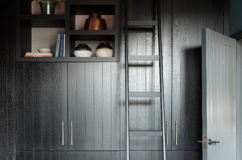 A dark bedroom design with fitted wardrobes and open shelving.