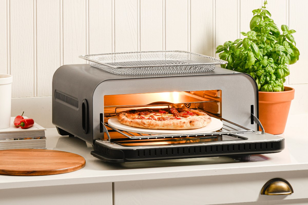 A small pizza appliance in a classic kitchen with white wall panelling behind it. 