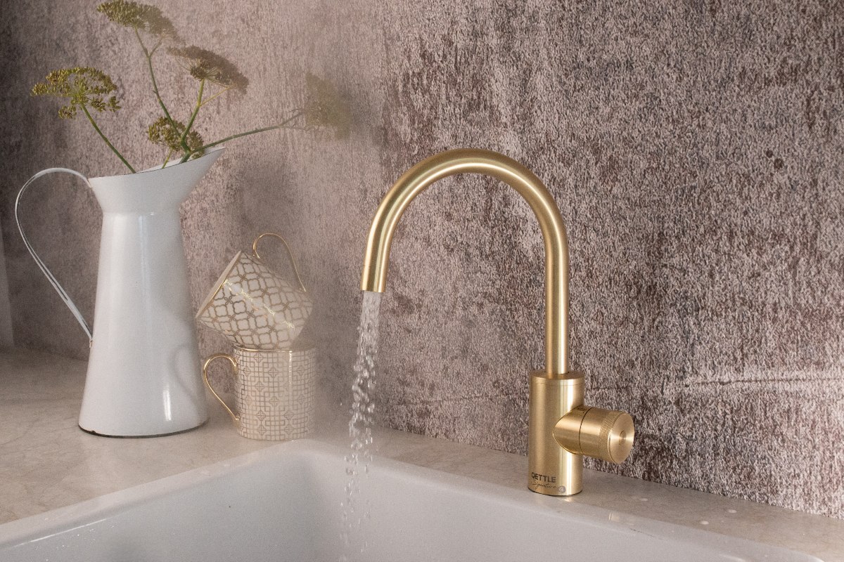 A sink zone with a compact tap in a gold finish.