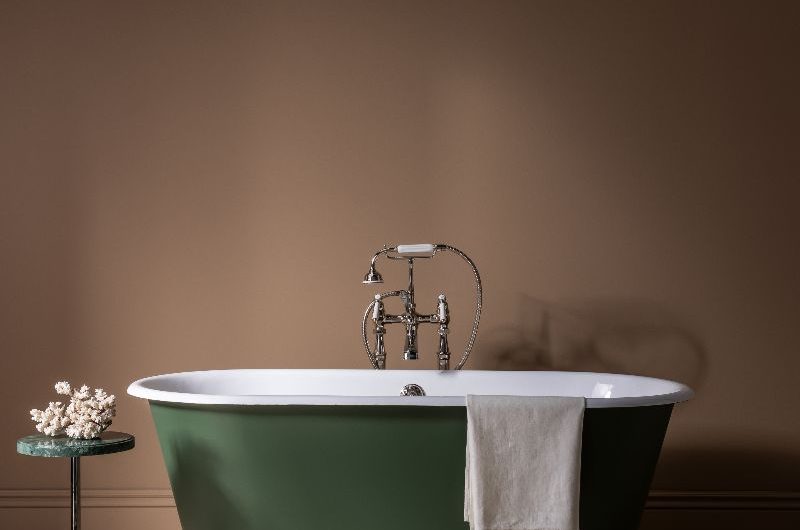 A green bathtub with round feet in a warm neutral scheme.