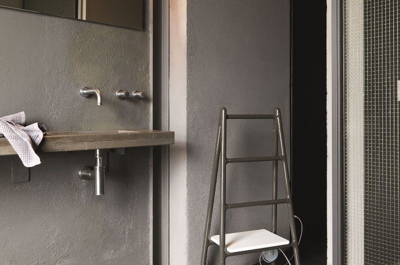 An industrial-style bathroom with chrome finishes and a heated towel rail.