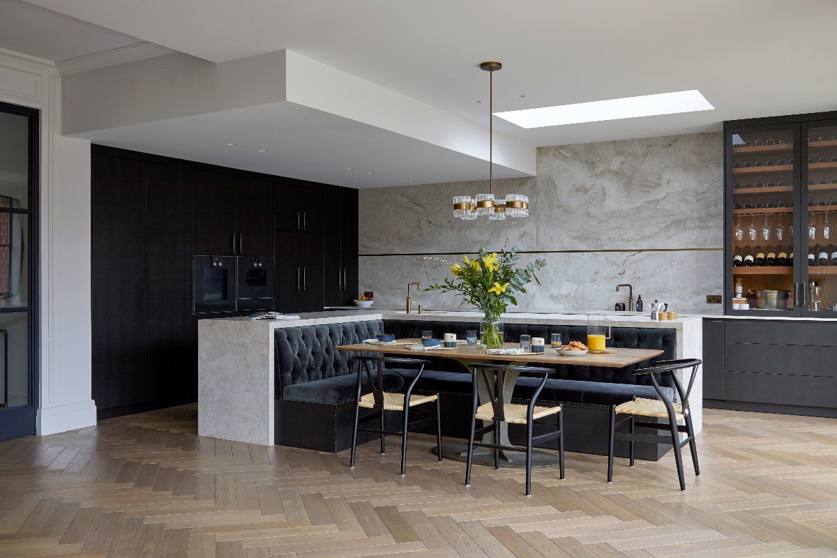 A sophisticated scheme with a dark floor-to-ceiling cabinetry tun, pale grey base units with a wine bar at the end, and a central unit with seating.