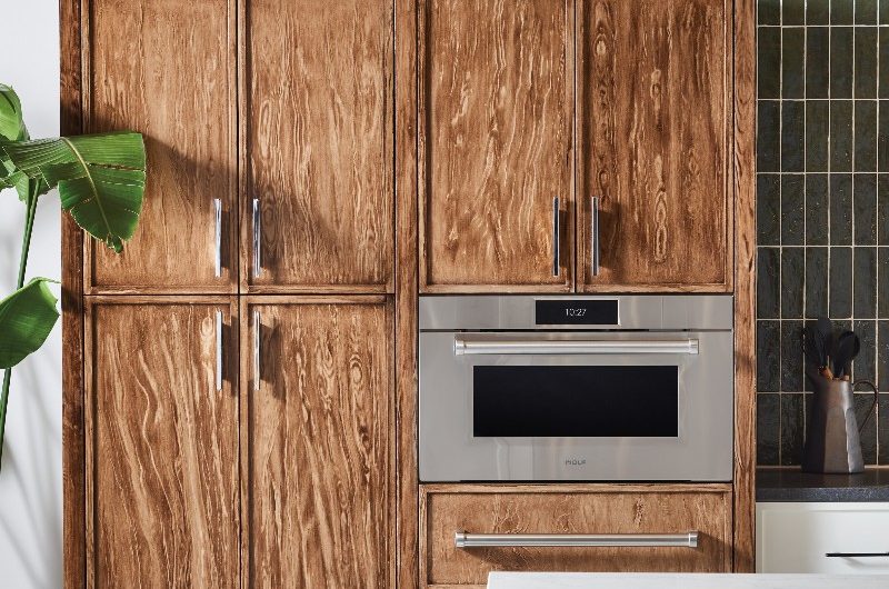 A grainy wood freestanding unit with stainless steel cooking appliance, and chrome handles in a classic-contemporary scheme.