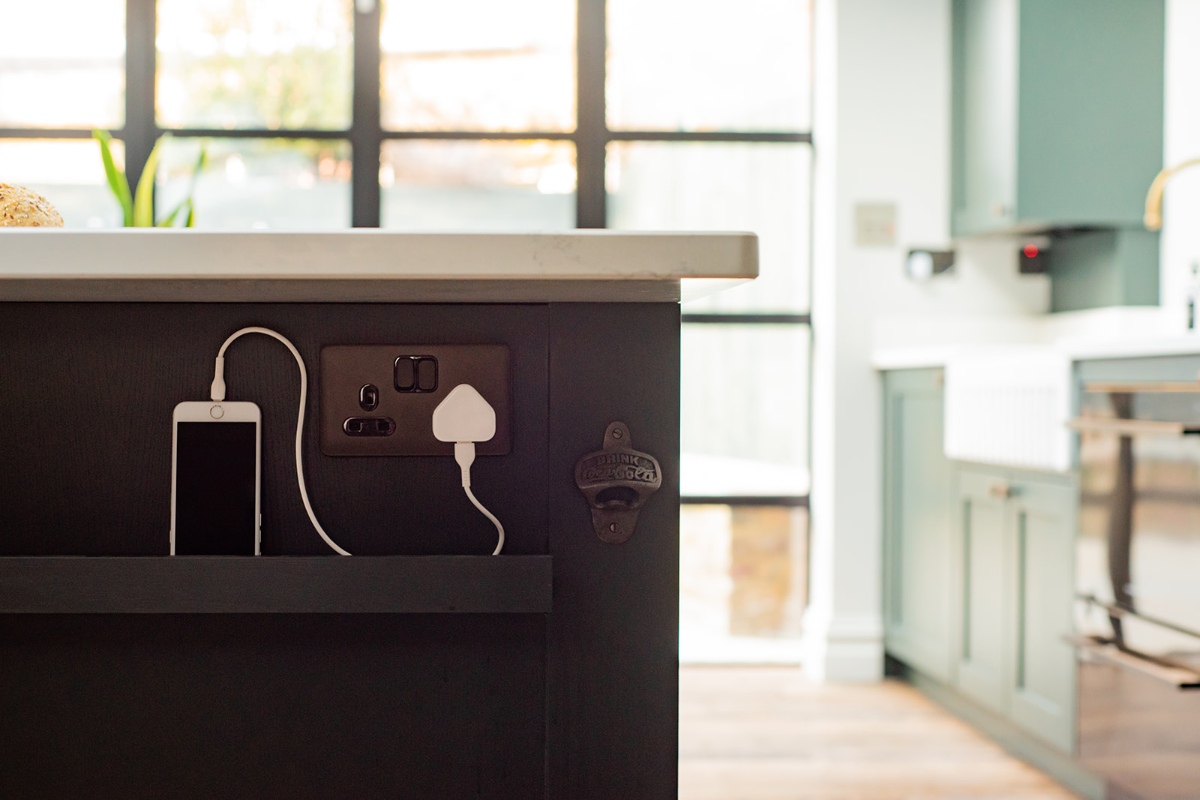 A classic design with a dark island with a phone plugged in the power plug.