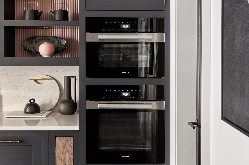 A cooking zone with built-in appliances in classic cabinetry with open shelving for displaying decor.