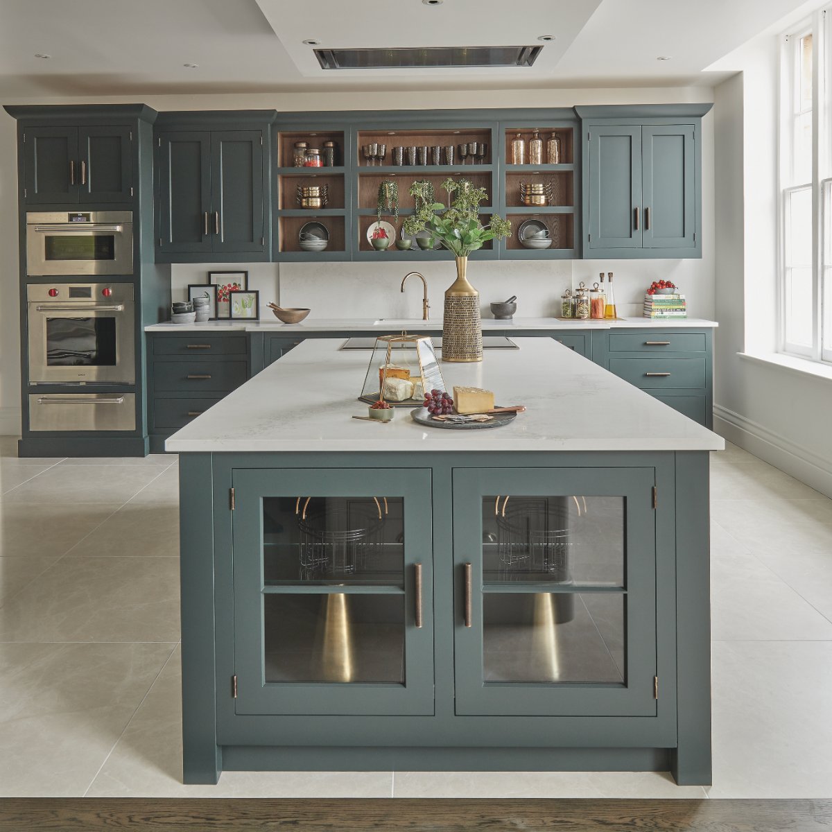 Classic green cabinetry with open shelving, drawers, door fronts, and built-in appliances.