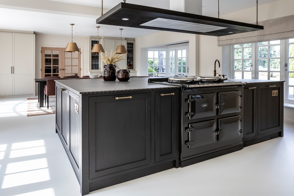 A statement kitchen island with a black range cooker, an extractor unit above it, and a nickel tap.
