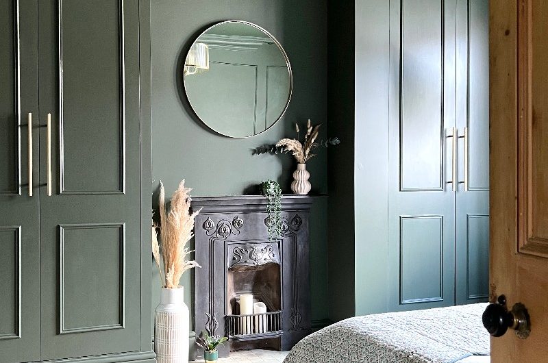 Calming green bedroom project with built-in wardrobes, fireplace, and a low-platform bed.