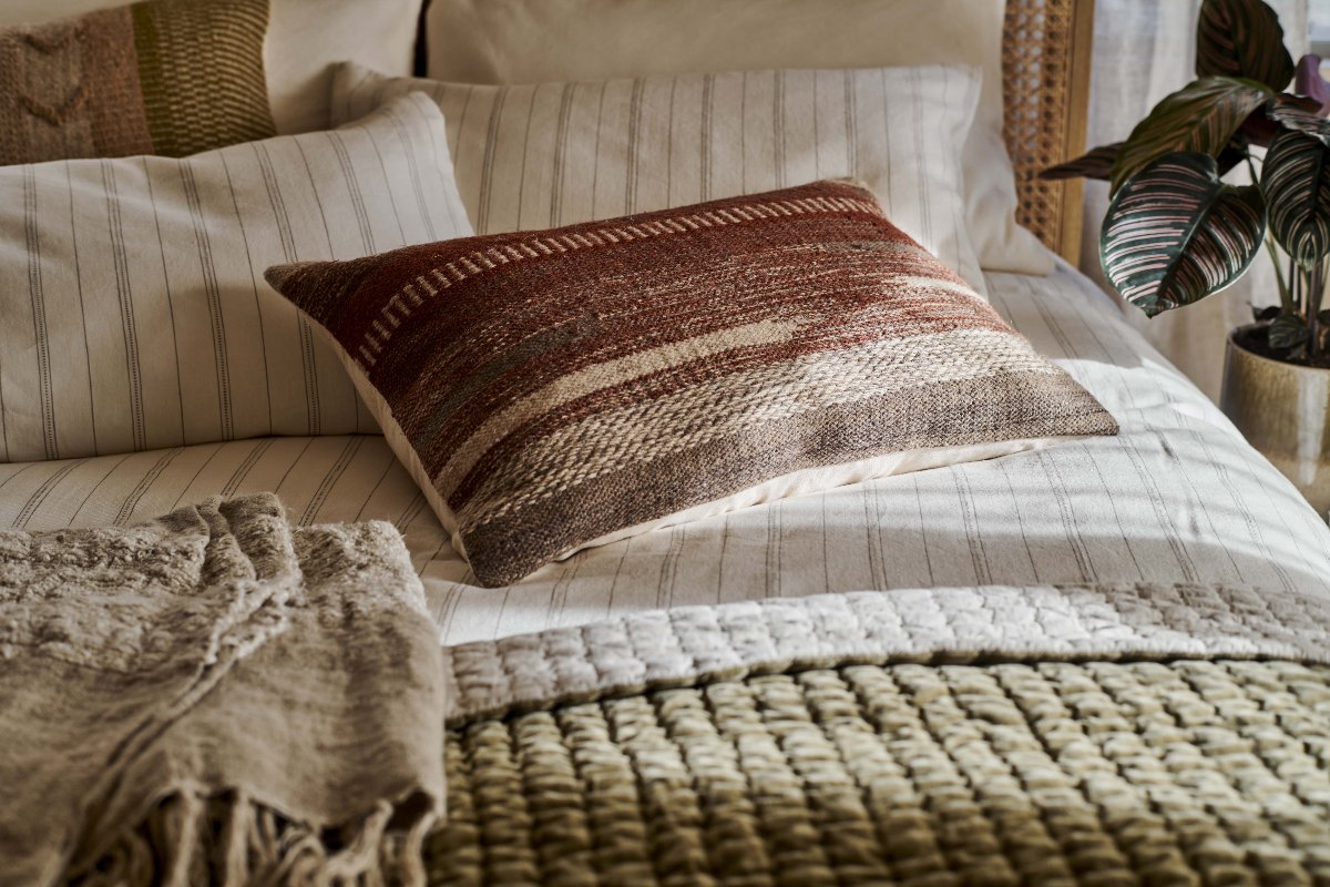 A wool cushion cover in a neutral bedroom design.