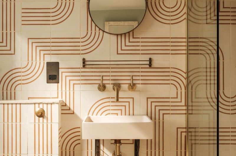 An art deco bathroom design with patterned tiles, elegant sanitaryware and brushed brass finishes.