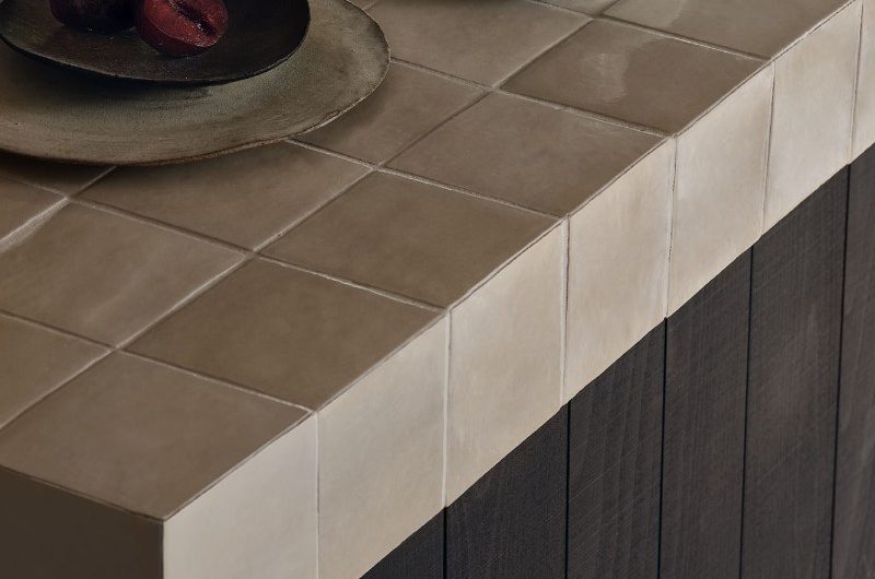 Closeup at porcelain zellige slabs on a wooden unit.