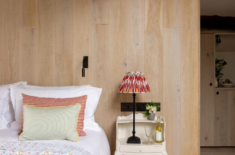 Bedroom design drenched in blonde wood with a small bedside table and low platform bed.