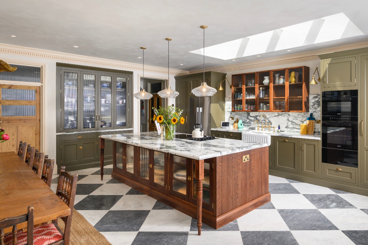 A large open-plan kitchen with an eclectic feel, a central wood island, checkerboard flooring, and contemporary features.