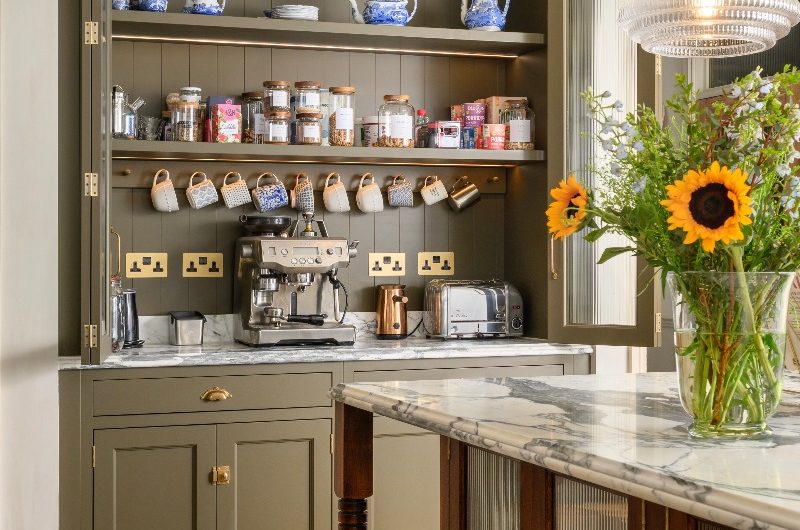 An open breakfast dresser housing cups, tea essentials, small appliances, a marble worktop, and power sockets.