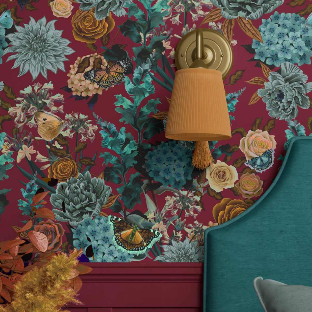 Closeup at a burgundy wallpaper with moody florals in turquoise and ochre shades, with a wall light and turquoise bed frame.