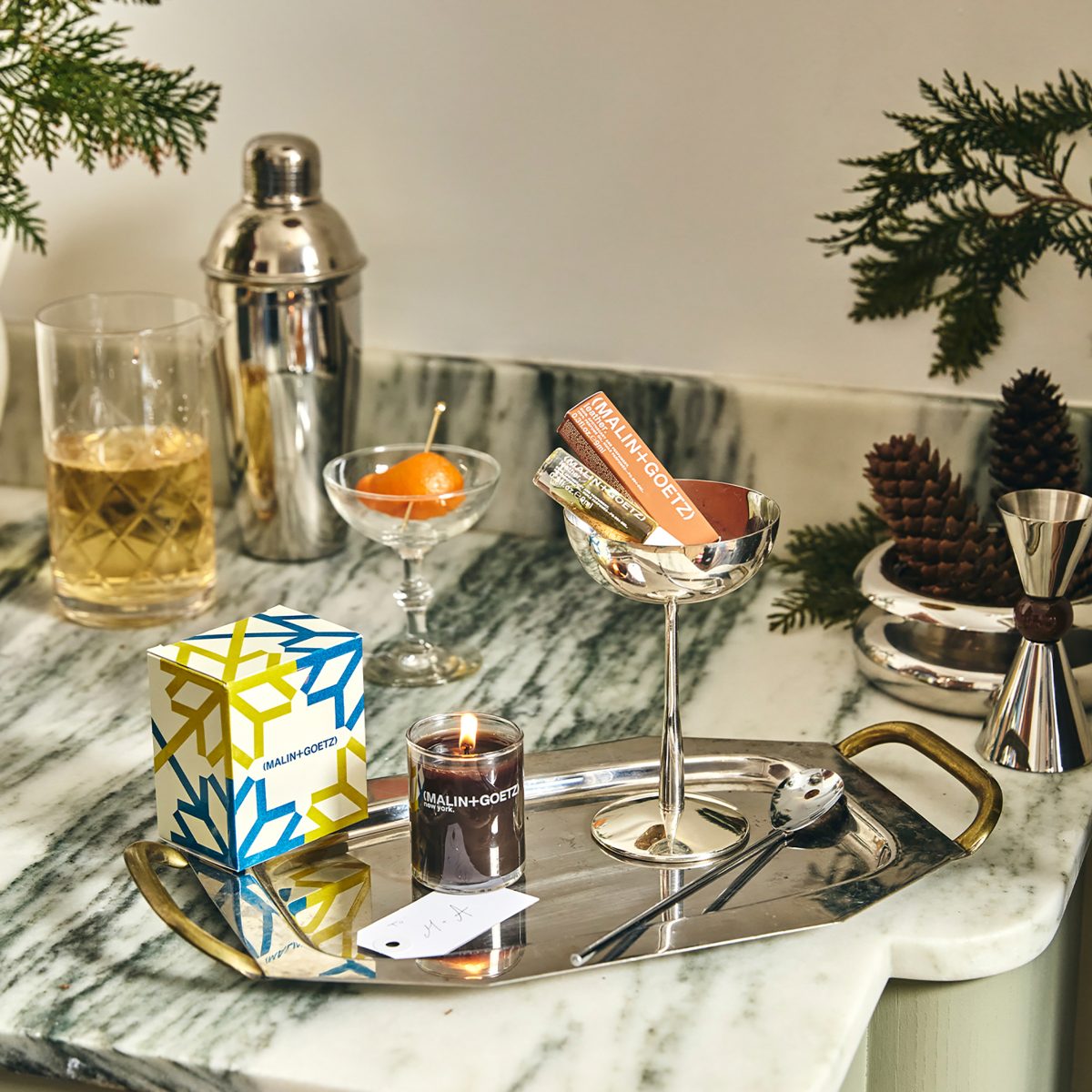 A marble worktop with a stylish chrome tray with a glass and candle and oil gift set.