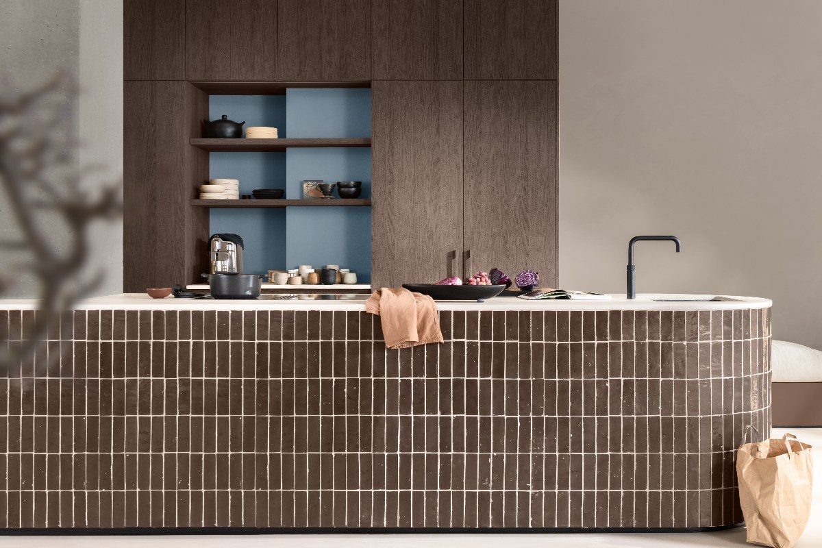 A neutral scheme with wood furniture and a central unit with space for food prep, cooking, and a compact sink and tap zone.