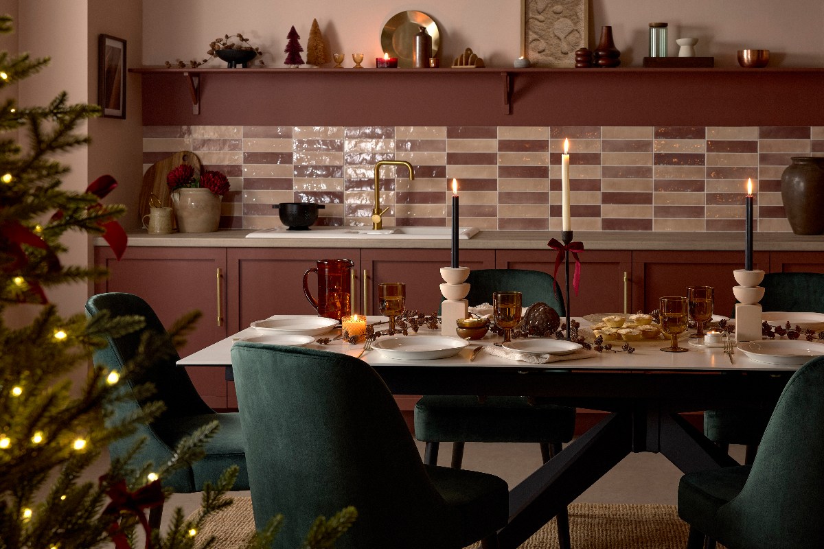 Kitchen-diner with red cabinetry, checkered metro slab tiles, and an extendable table with green velvet chairs.