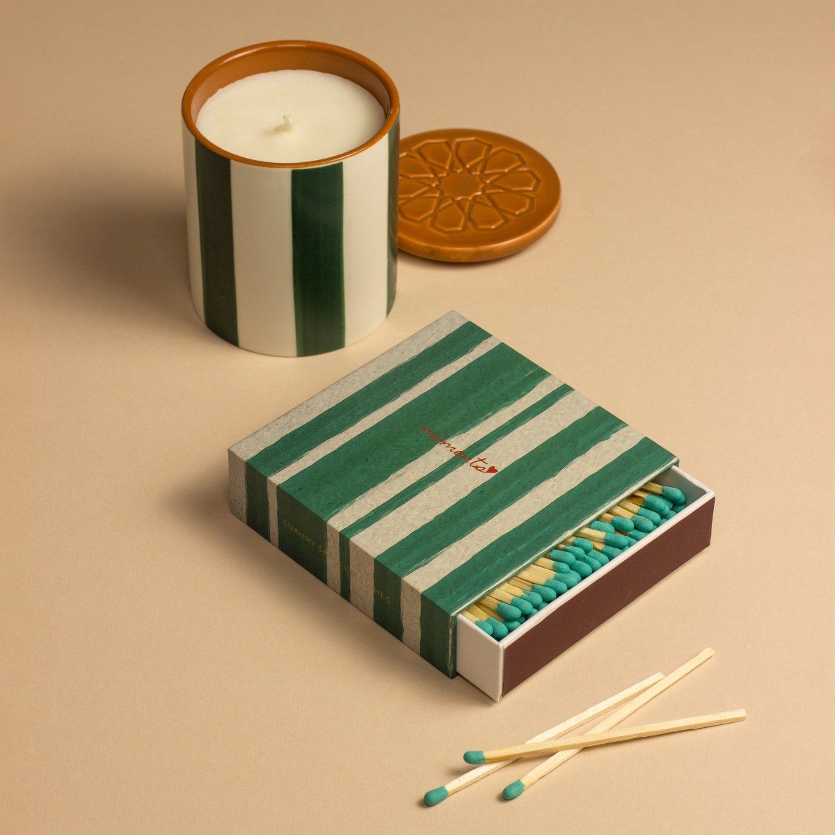 A green striped candle with a striped green matchbox.