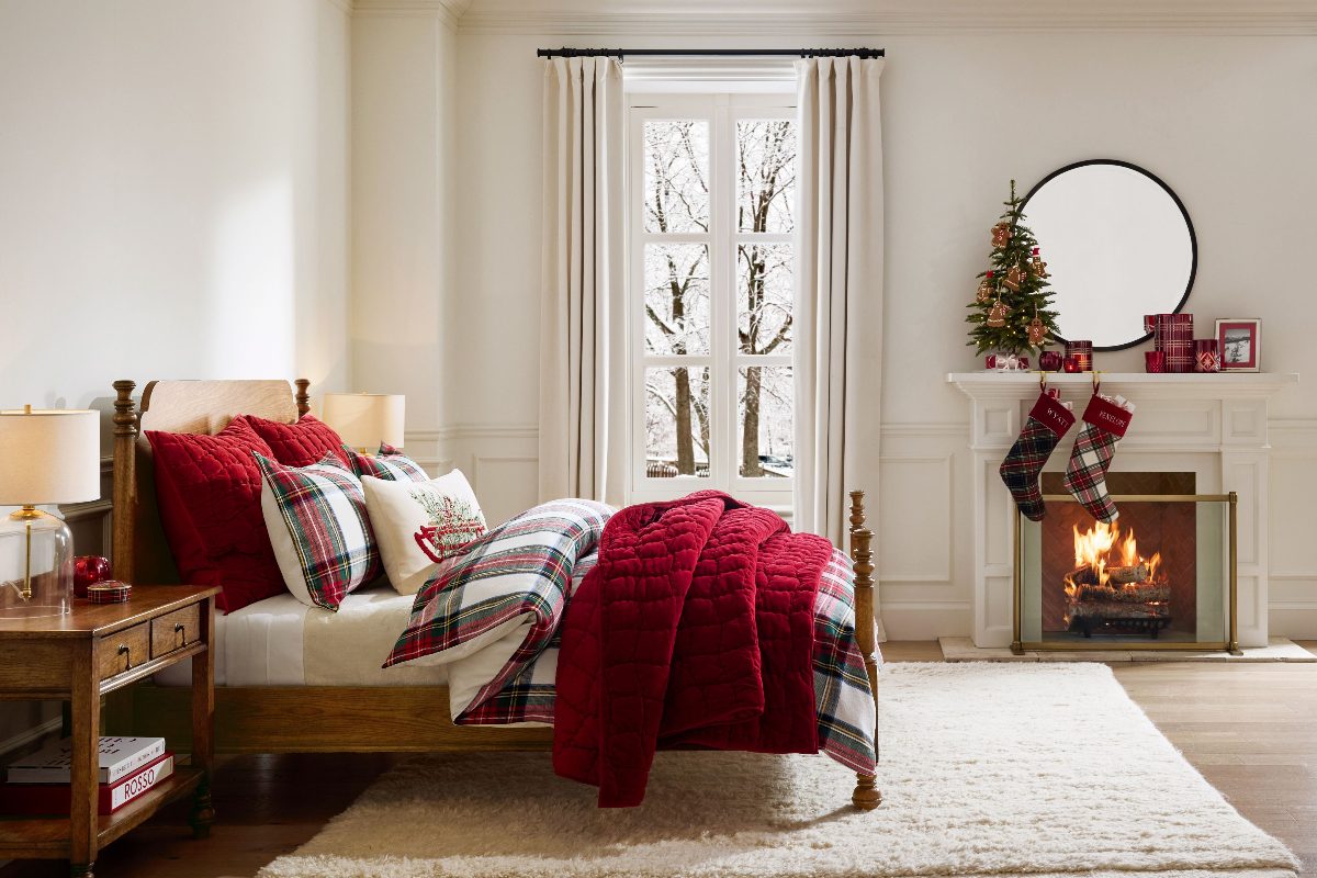 A classic Christmas bedroom with red, white, and green plaid soft furnishings, and a fireplace.
