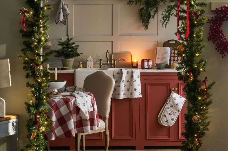A red and neutral kitchen design with an entryway decorated with Christmas garlands and red bows.