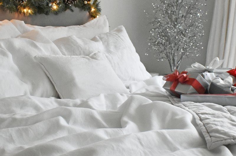 A clean and crisp bedroom design with white bedding and festive decor.