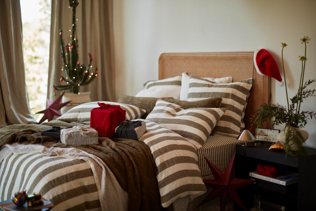 A neutral bedroom design with a striped bed linen set and festive decorations.