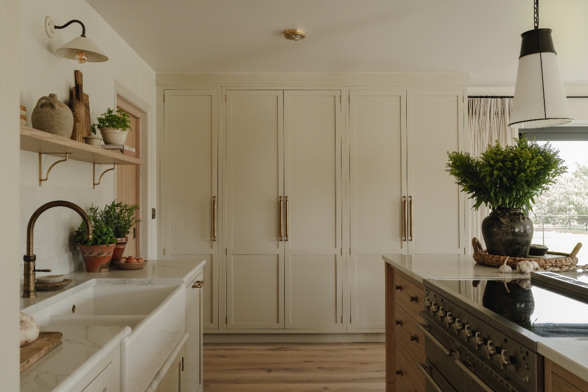 A closeup at a tall run of cabinetry with a central island with a range cooker, and a sink area behind it.
