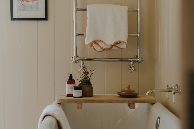 A calm bathroom with a freestanding bath, a chrome radiator, and spa-like accessories.