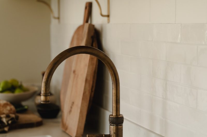 Closeup at a brass boiling-water tap above a double bowl sink.