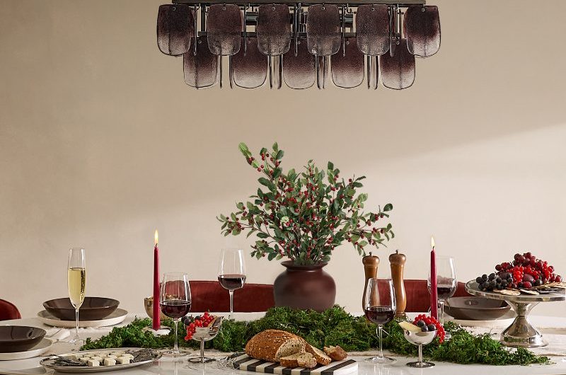 A modern dining room with a fluted wood dining table, red velvet chairs, cream velvet bench and festive decorations.