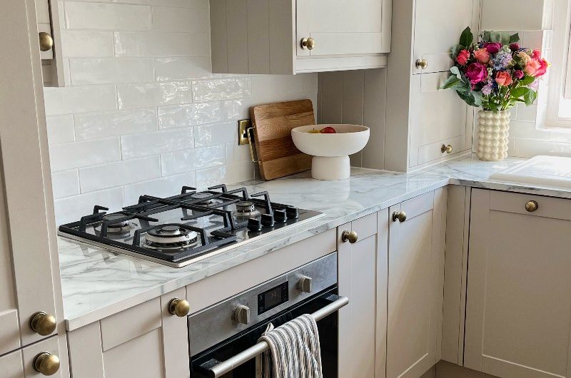 A home renovation with a neutral kitchen, herringbone flooring and white tiles and worktops.