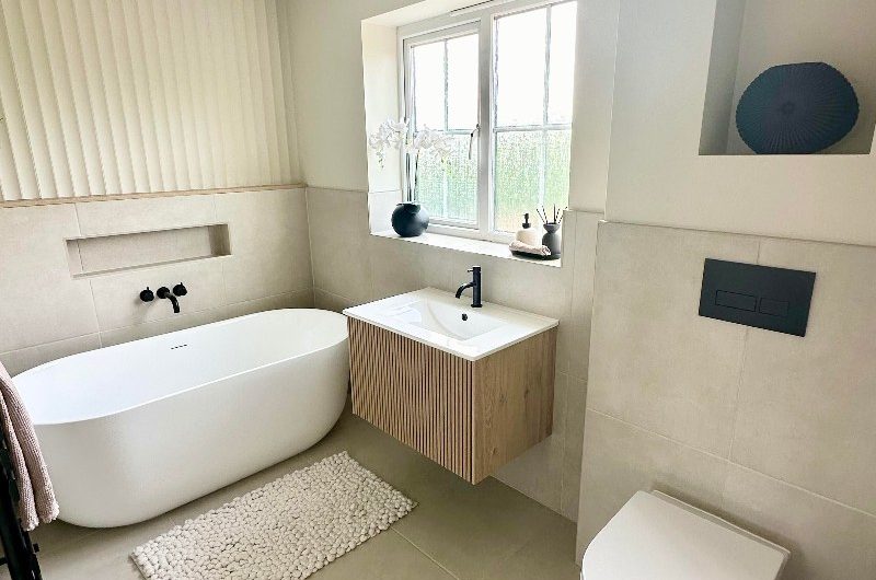 A spa-like bathroom renovation with a freestanding bath and a fluted wood vanity.