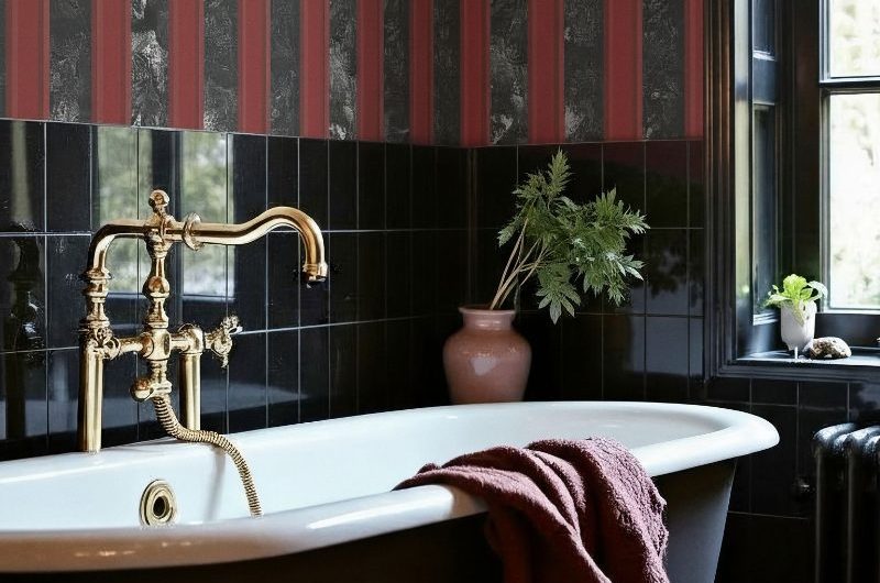 Bathroom design with black tiles, moody wallpaper, a freestanding tub and gold bath filler.