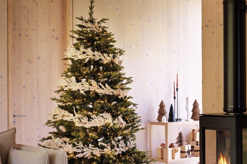 Scandinavian-inspired home Christmas decorating ideas with a wood fire stove, and layered, tactile materials, from cushions to throws.