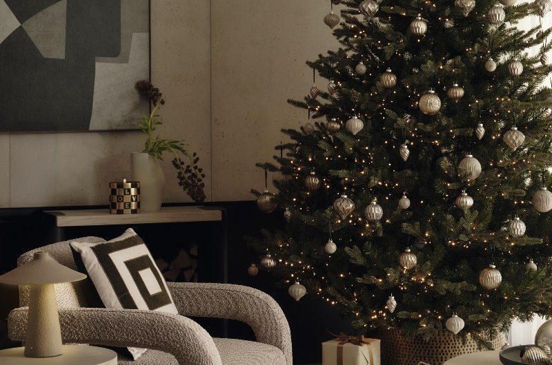 An elegant home decorated for Christmas with a monochromatic palette, plush furnishings, and a tall tree.